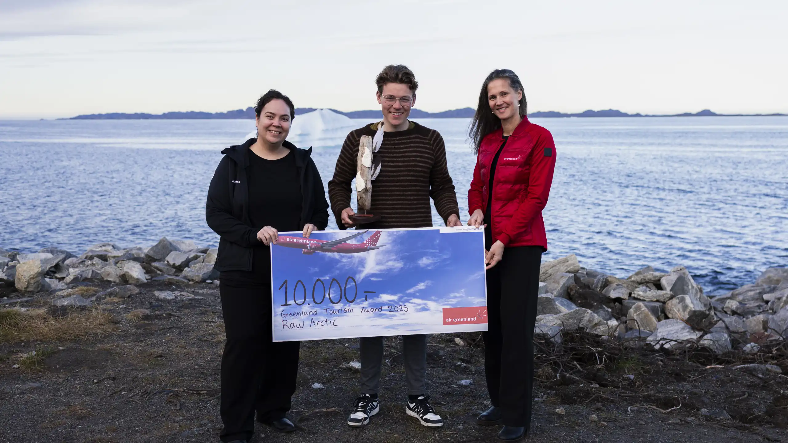 Isak Brandt Hansen (center), co-owner of Raw Arctic, receives the Greenland Tourism Award 2025 and a travel gift card worth DKK 10,000 from Air Greenland on behalf of Raw Arctic. The award is presented by Tupaarnaq Tróndheim from Visit Greenland (left) and Katja Vahl from Air Greenland (right).