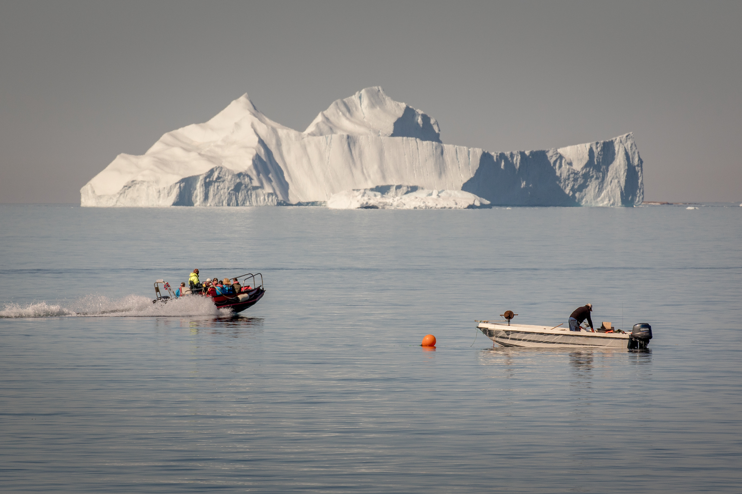 A Tenderboat From MS Fram Going Past A Fisherman At Work In Upernavik In Greenland